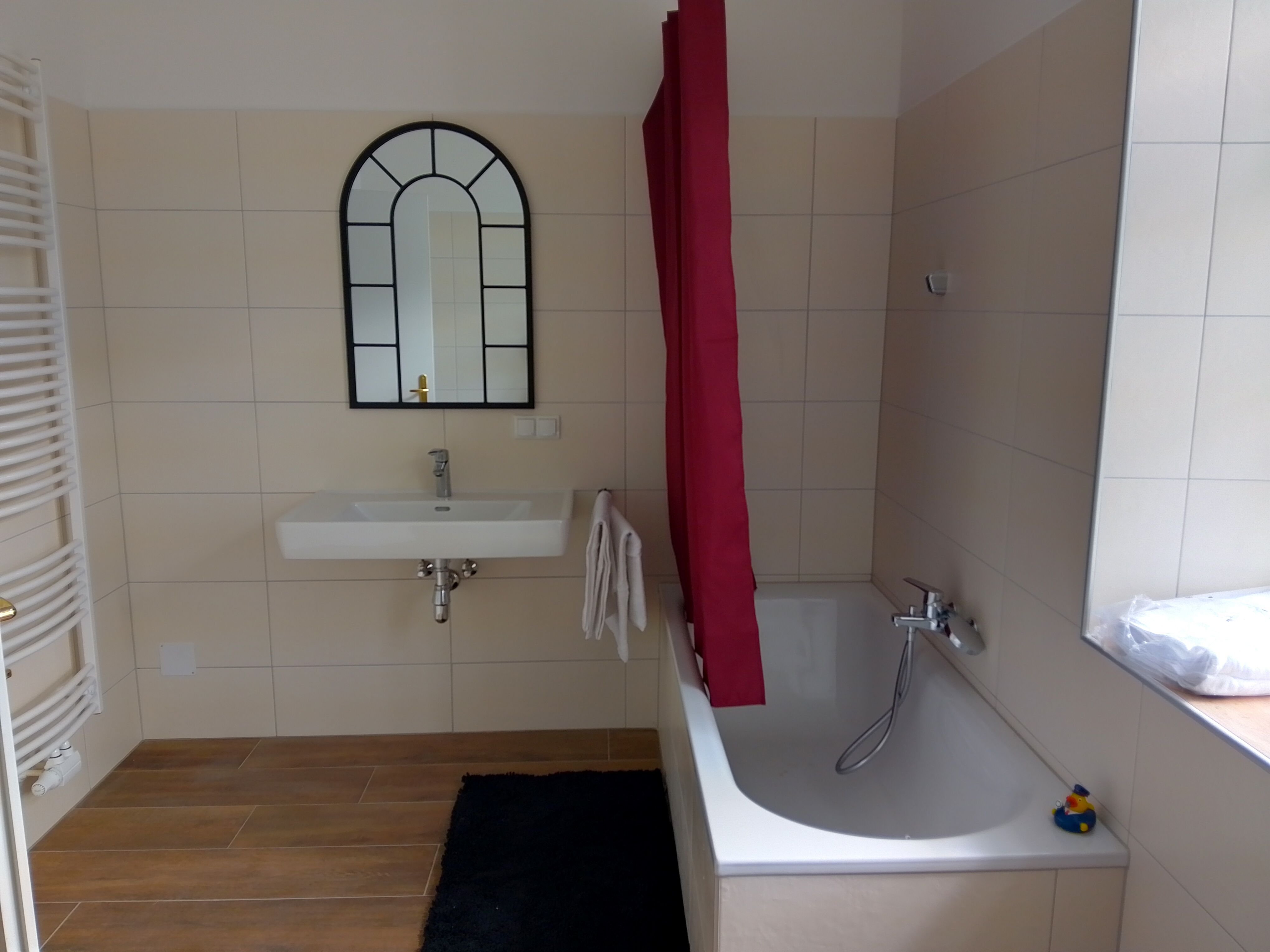 Modernes Badezimmer mit Badewanne, Waschbecken und Spiegel.