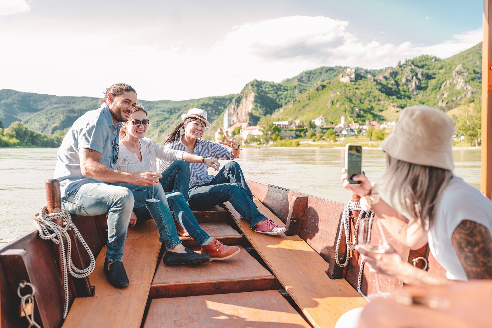 Eine Gruppe von Freunden genießt die entspannte Atmosphäre auf einem Boot, umgeben von der atemberaubenden Natur. Die sanften Wellen des Wassers und die majestätischen Berge im Hintergrund schaffen eine perfekte Kulisse für unvergessliche Momente. Lachen und Freude sind in der Luft, während sie die Schönheit der Landschaft erleben.