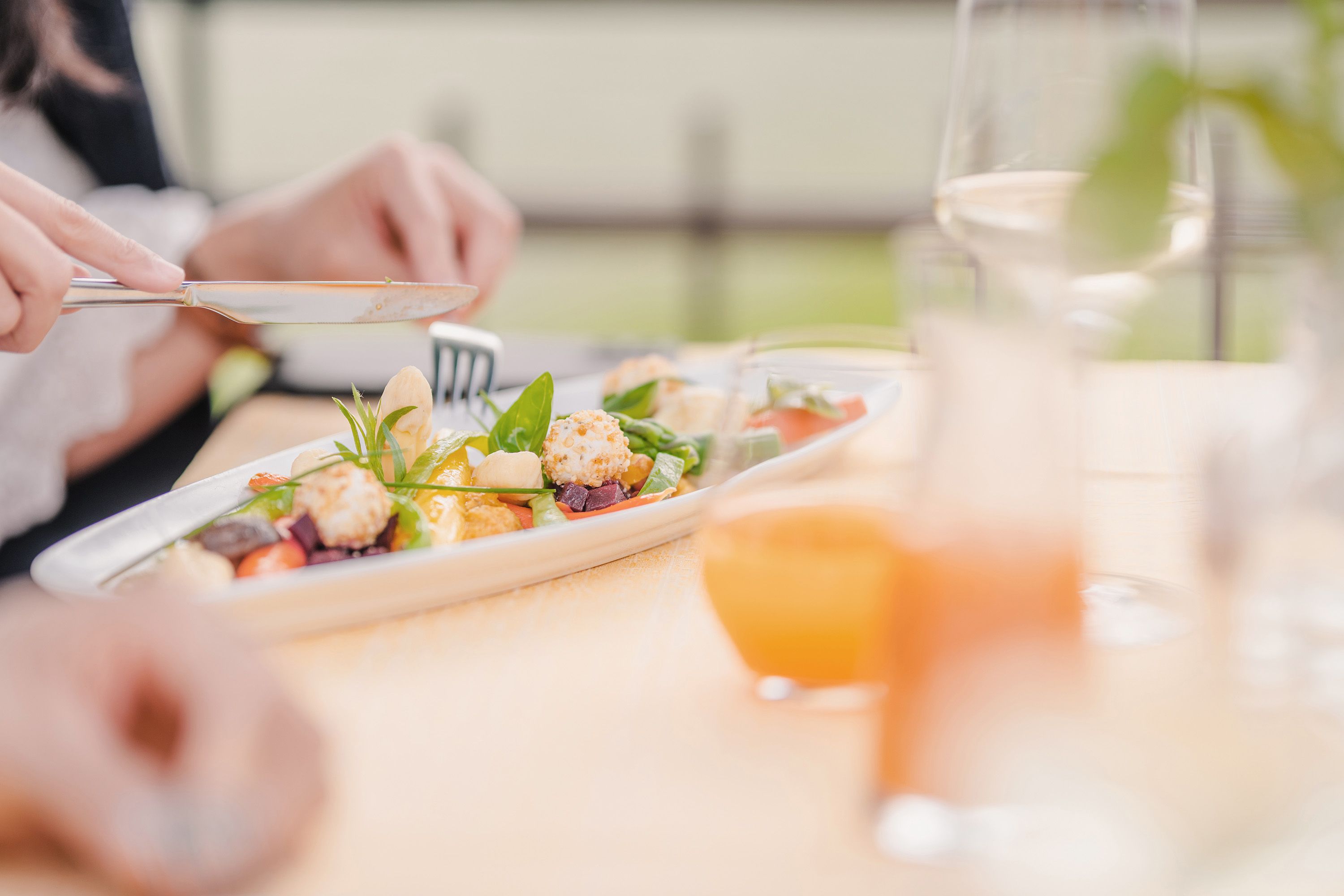 Ein schon dekorierter Teller mit einer Vorspeise und einem Marillensaft im Hintergrund