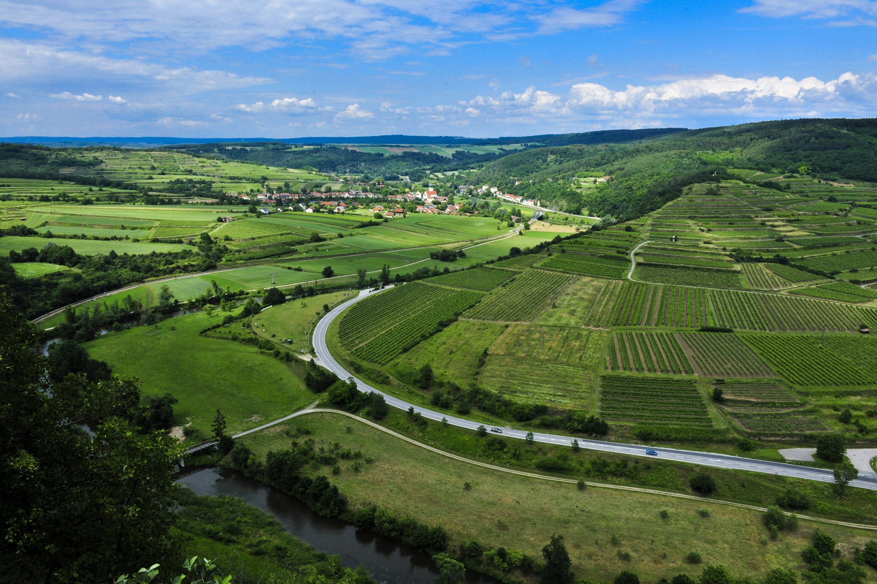 Landschaft im Naturpark Kamptal Schönberg mit Feldern, Straßen und einem Fluss.