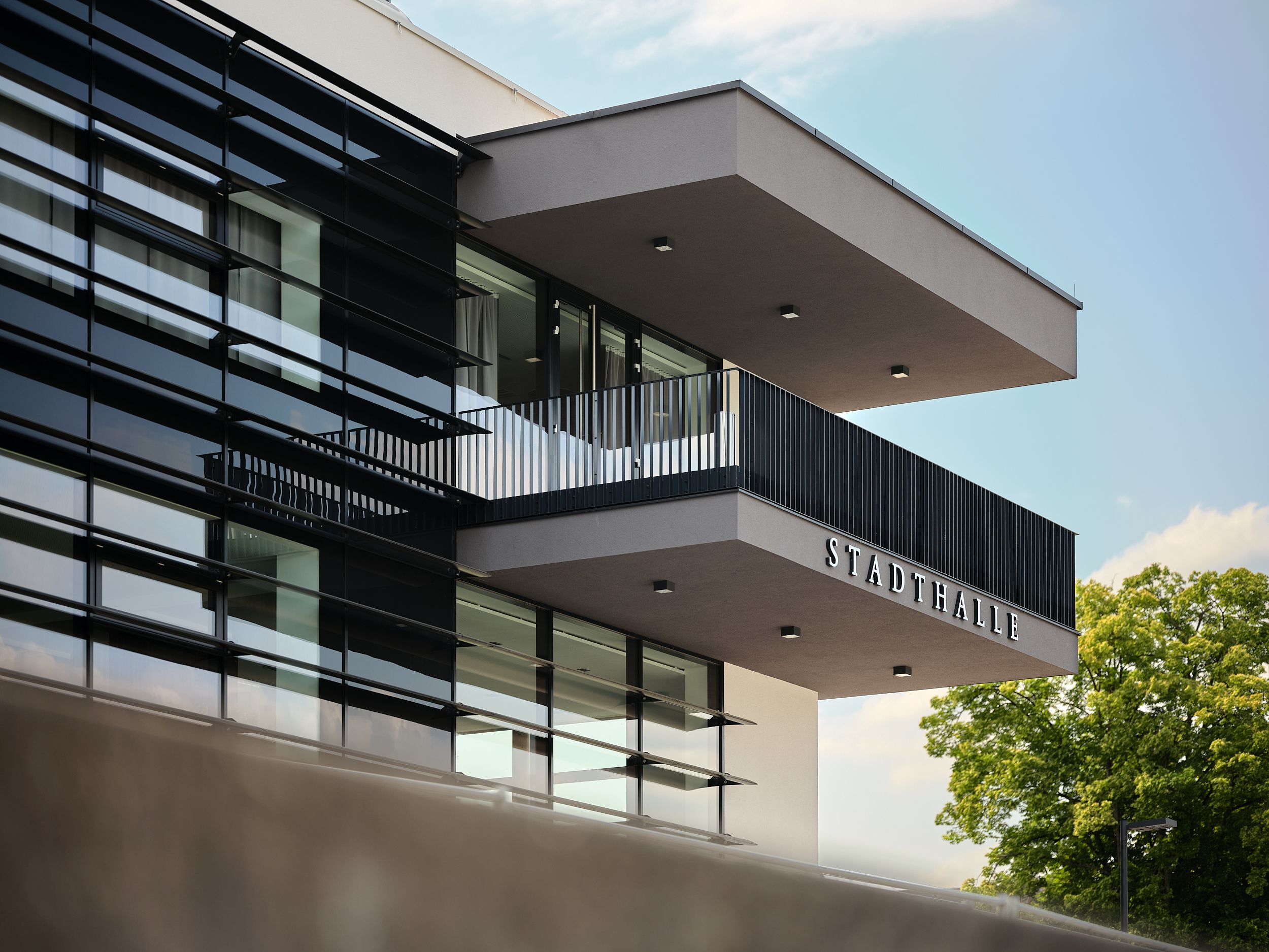 Modern exterior view of Stadthalle Ybbs with glass façade and balcony.