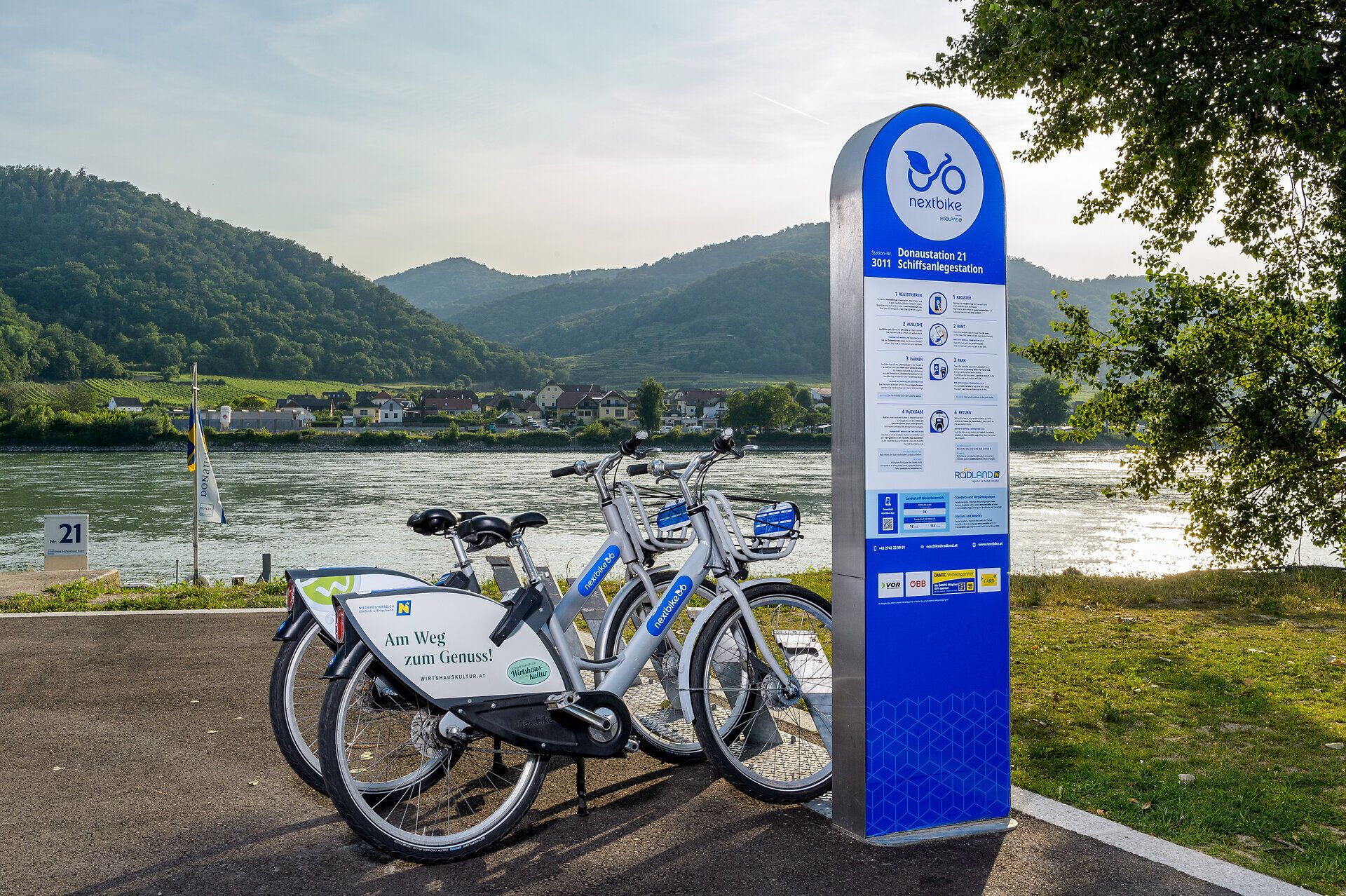 Entlang der sanften Wellen der Donau stehen Fahrräder bereit, um die malerische Landschaft zu erkunden. Die umliegenden Hügel laden dazu ein, die Schönheit der Natur zu genießen und die frische Luft zu atmen. Ein idealer Ort, um die Wirtshauskultur Niederösterreichs zu erleben und die Seele baumeln zu lassen.