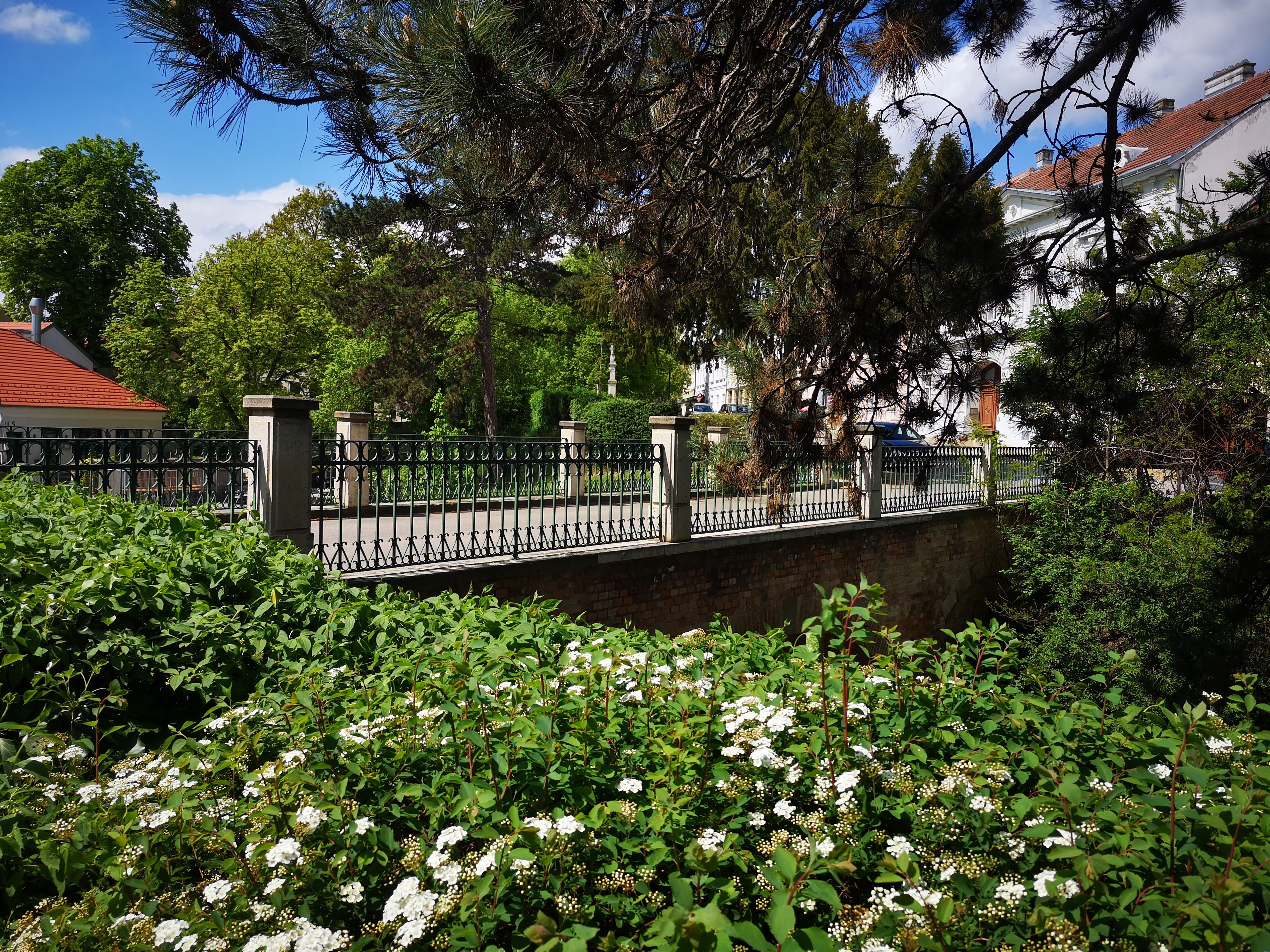 Idyllische Brücke, eingebettet in üppige Blumen und grüne Bäume.
