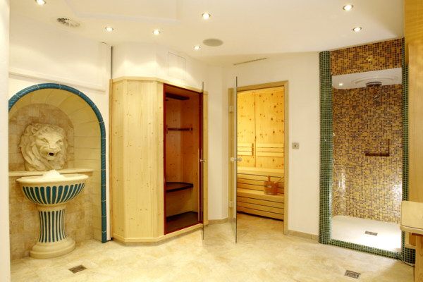 Belső nézet a szaunával, zuhanyzóval és oroszlánfejes szökőkúttal ellátott wellness-részlegről.