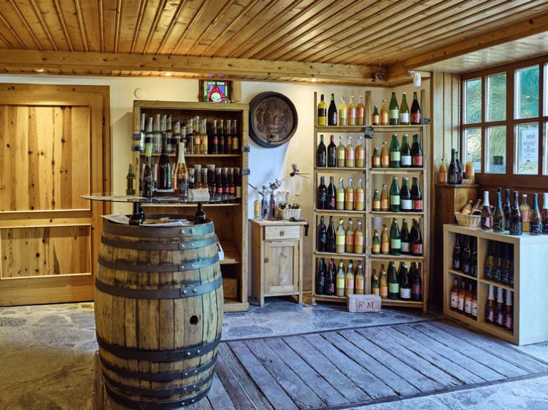 Innenansicht eines rustikalen Weinladens mit Holzregalen und Weinfässern.
