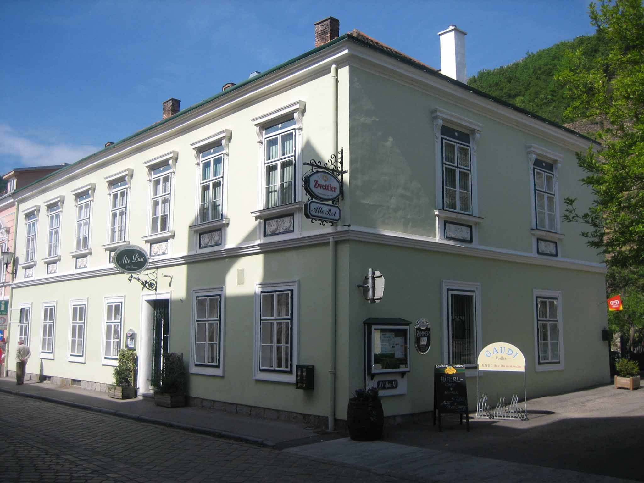 Historisches Gebäude mit grüner Fassade und mehreren Fenstern, beschildert als Gasthaus.