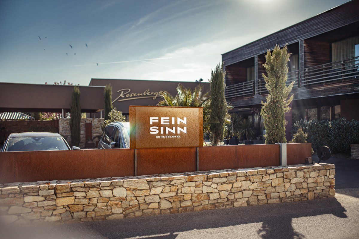 Eingang des Feinsinn Genusslokals mit moderner Architektur und Pflanzen.