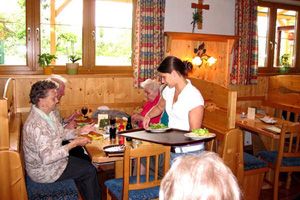 Innenansicht eines traditionellen österreichischen Heurigen mit Gästen und Bedienung.