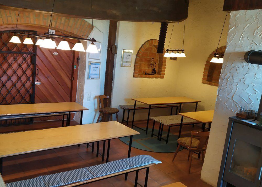 Innenansicht eines Heurigen mit Holztischen, Bänken und rustikaler Dekoration.