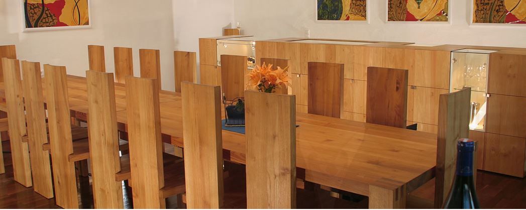 Holztisch mit Weingläsern in einem hellen Verkostungsraum, schlichtes und einladendes Ambiente für Weinproben.