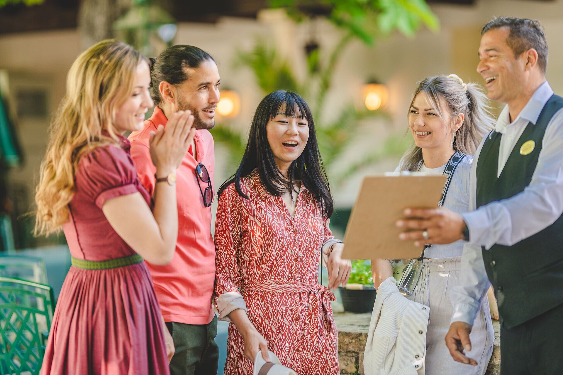 Der Kellner zeigt 4 Personen die Speisekarte.