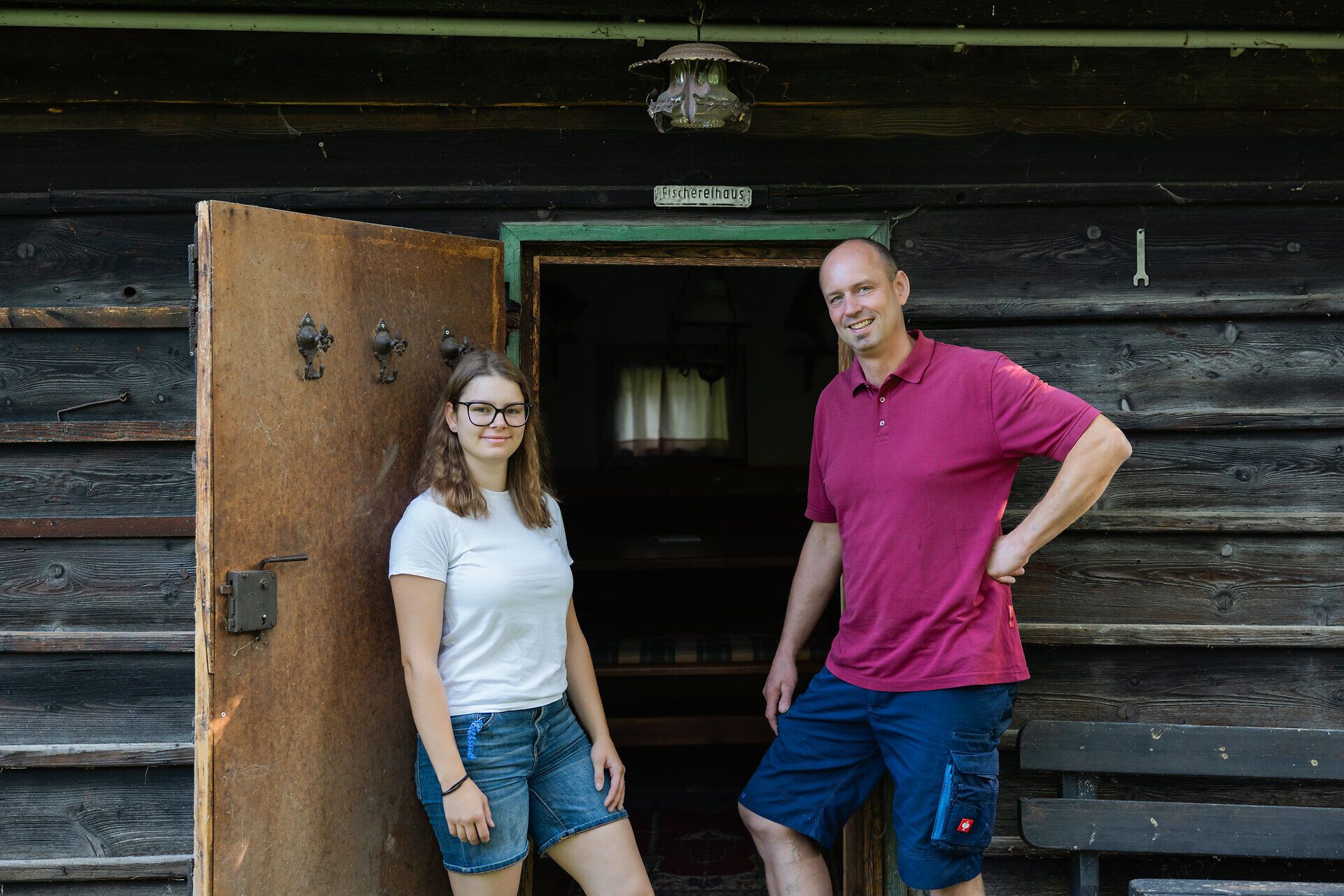 Tochter und Vater von der Fischwerkstatt posieren im Freien und blicken lächelnd in die Kamera.