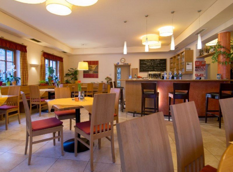 Innenansicht eines gemütlichen Restaurants mit Holzmöbeln und Bar.