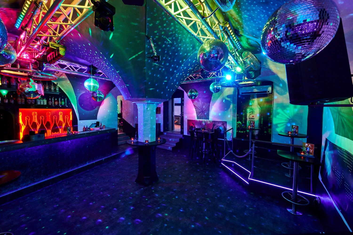 Innenansicht eines Clubs mit Discokugeln und bunter Beleuchtung.