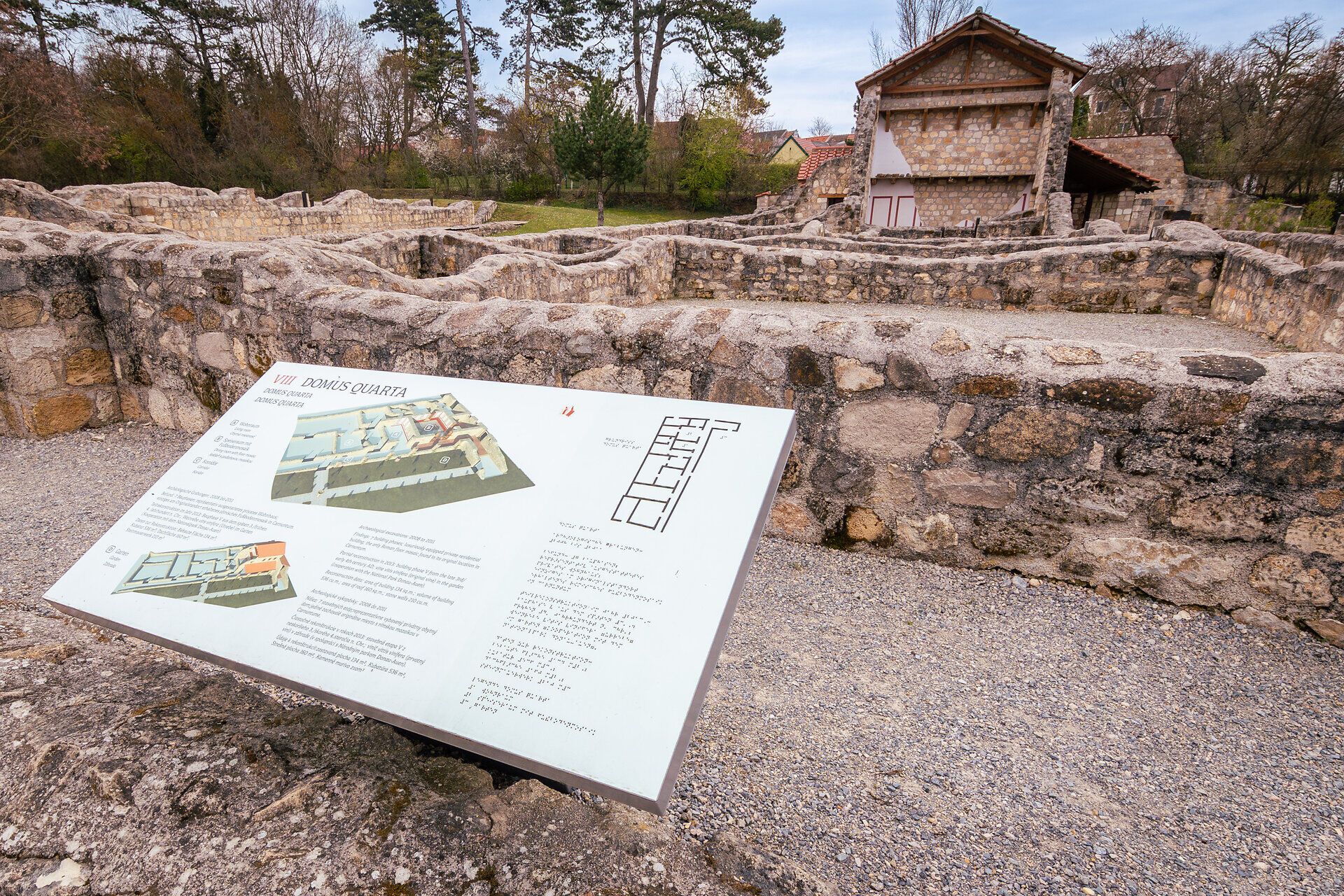 Außenaufnahme eines römischen Hauses. Im Vordergrund steht eine Beschreibungstafel.