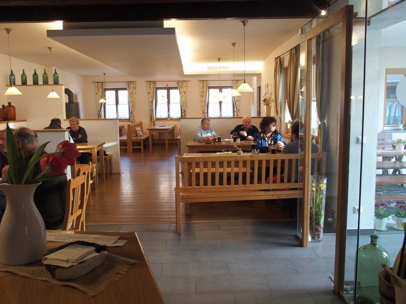 Innenansicht eines gemütlichen Heurigen mit Holzmöbeln und Gästen an Tischen.