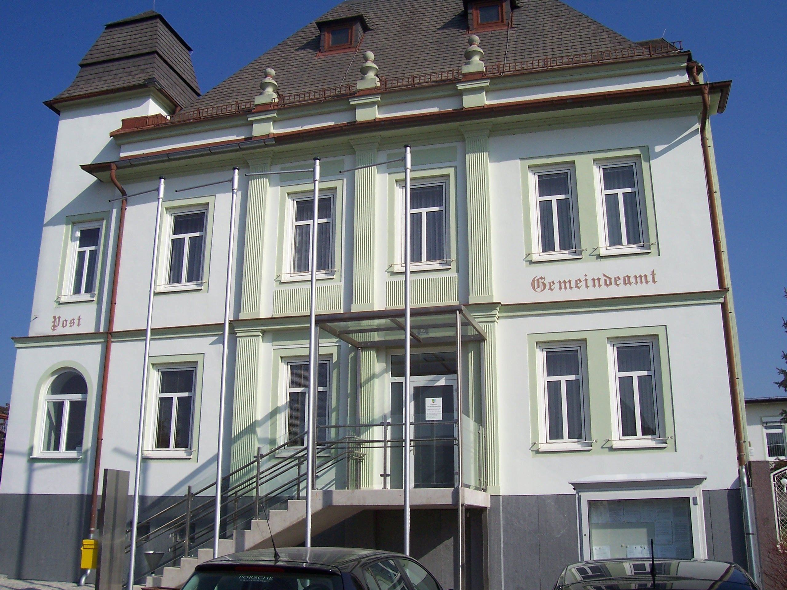Gemeindeamt Untersiebenbrunn mit Treppe und Fahnenmasten vor dem Gebäude.