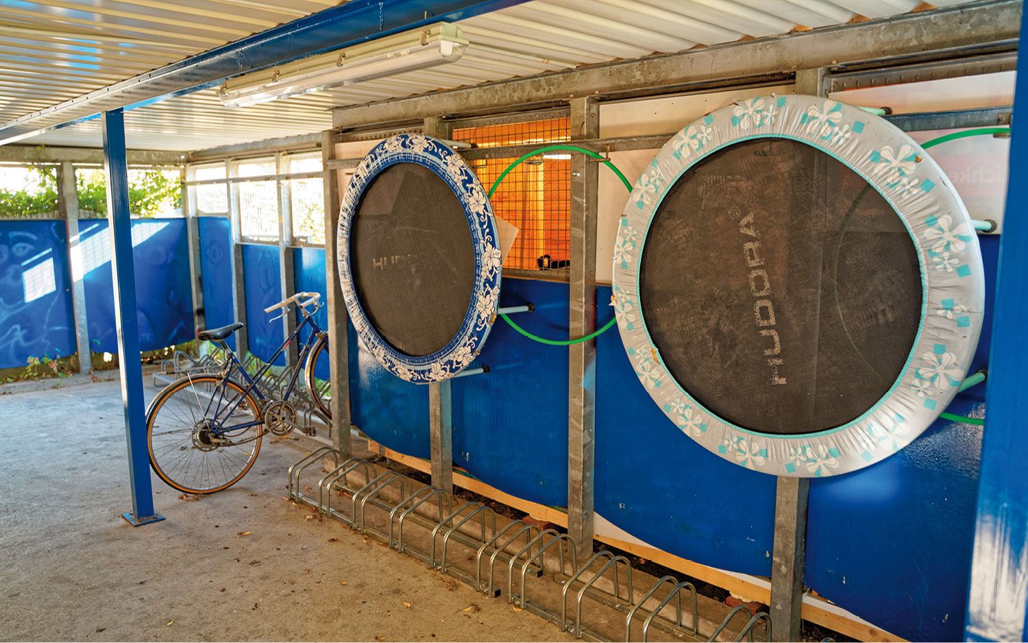 Fahrradgarage mit Trampolinen an der Wand.