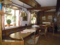 Ein traditionell eingerichtetes Zimmer mit Holzmöbeln, Pflanzen auf der Fensterbank und hängenden Lampen.