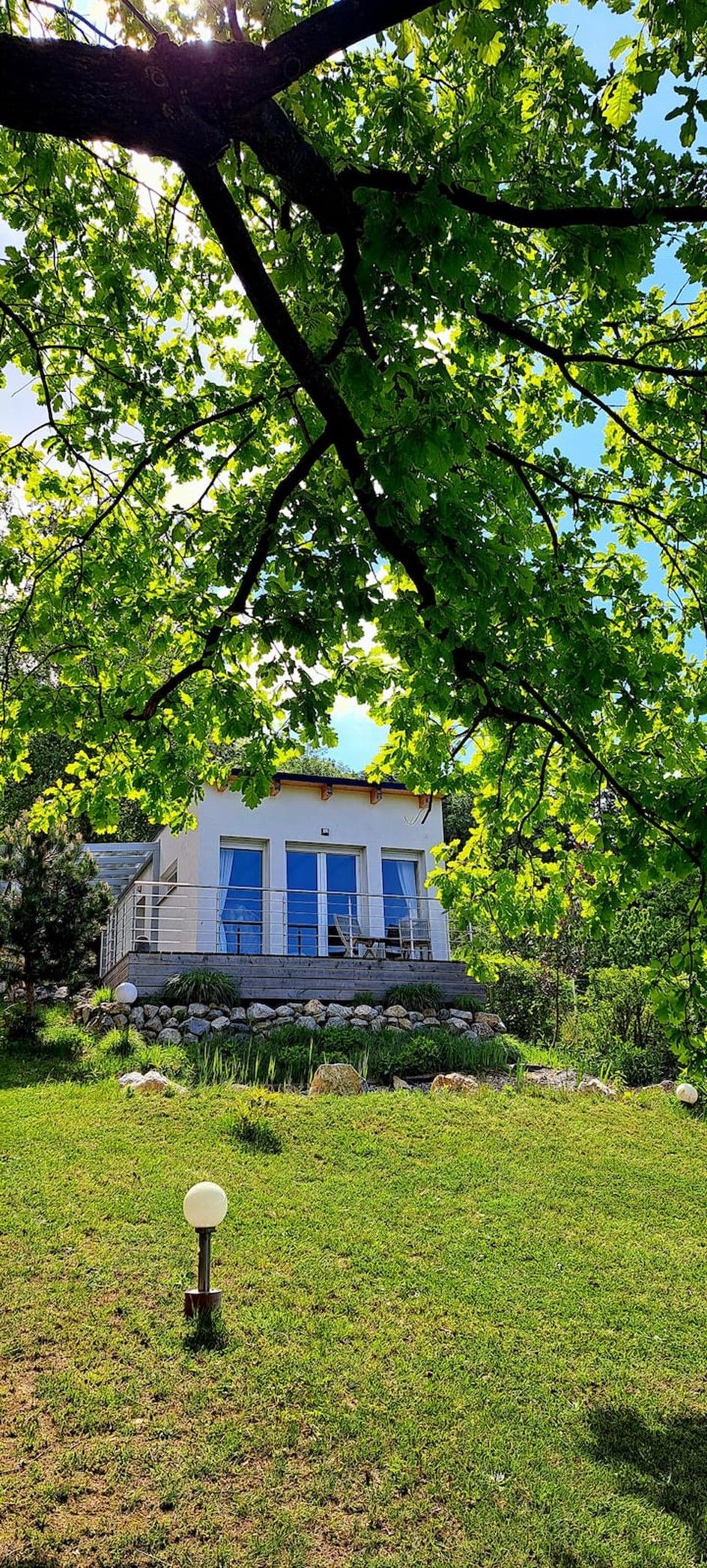 Ein modernes Chalet mit großer Fensterfront, umgeben von grüner Natur und Bäumen.
