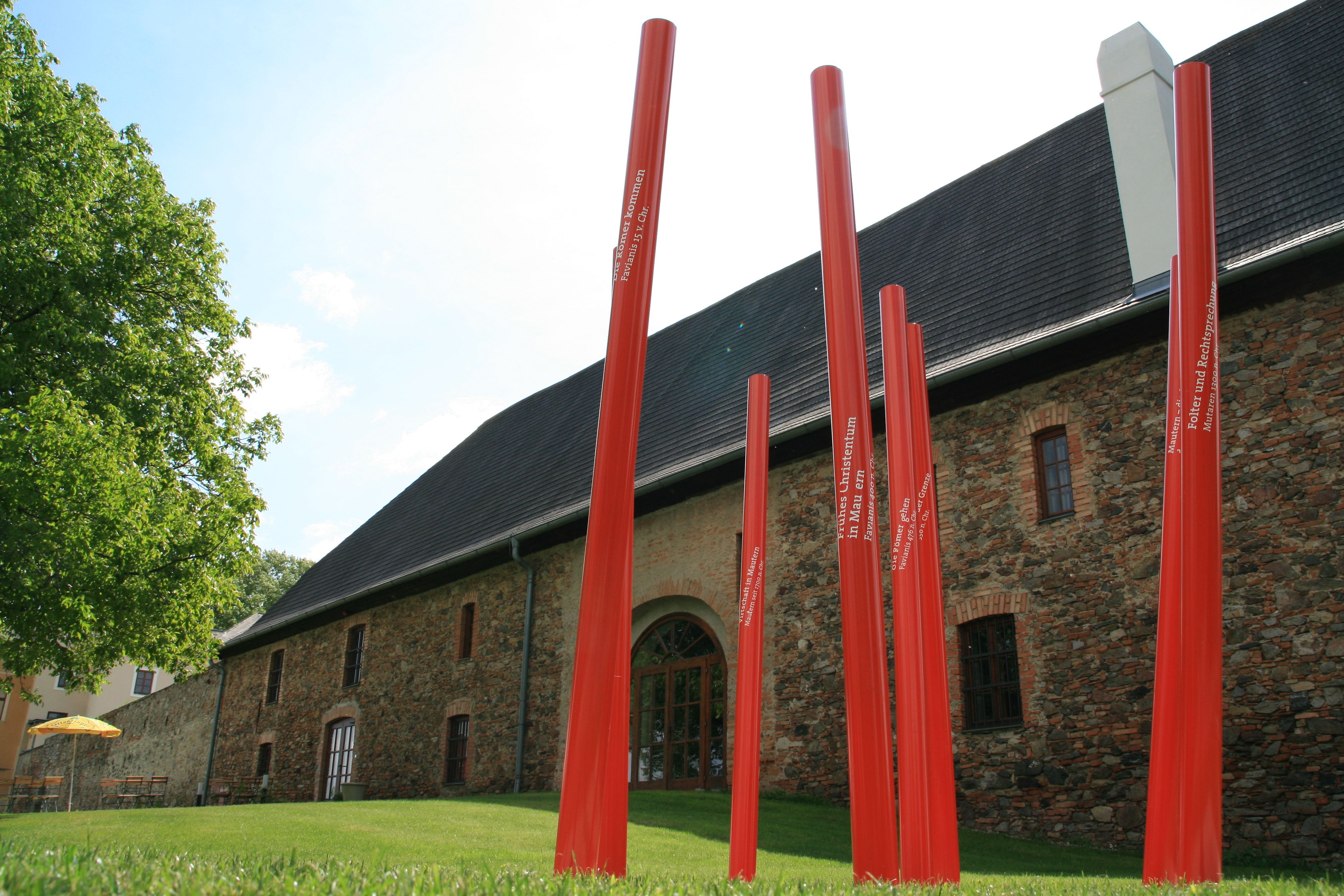 Rote Stangen vor einem historischen Gebäude in Mautern.