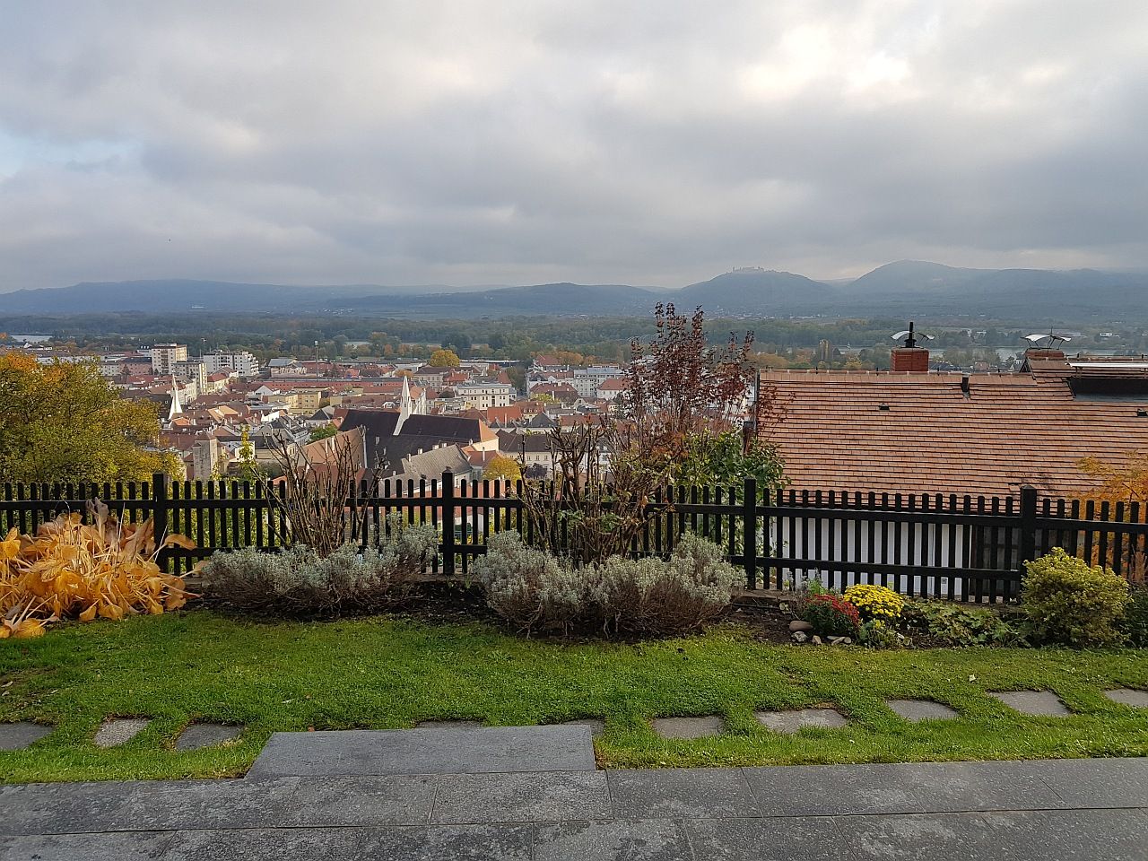 Blick über die Stadt Krems mit Häusern, Hügeln und bewölktem Himmel im Hintergrund.