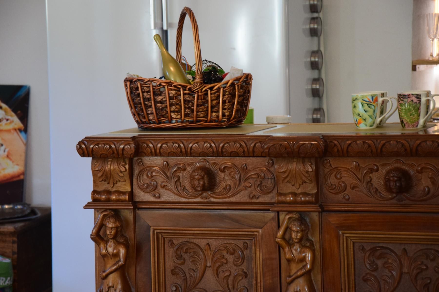 Ein geschnitztes Holzbuffet mit einem Korb und Tassen darauf.