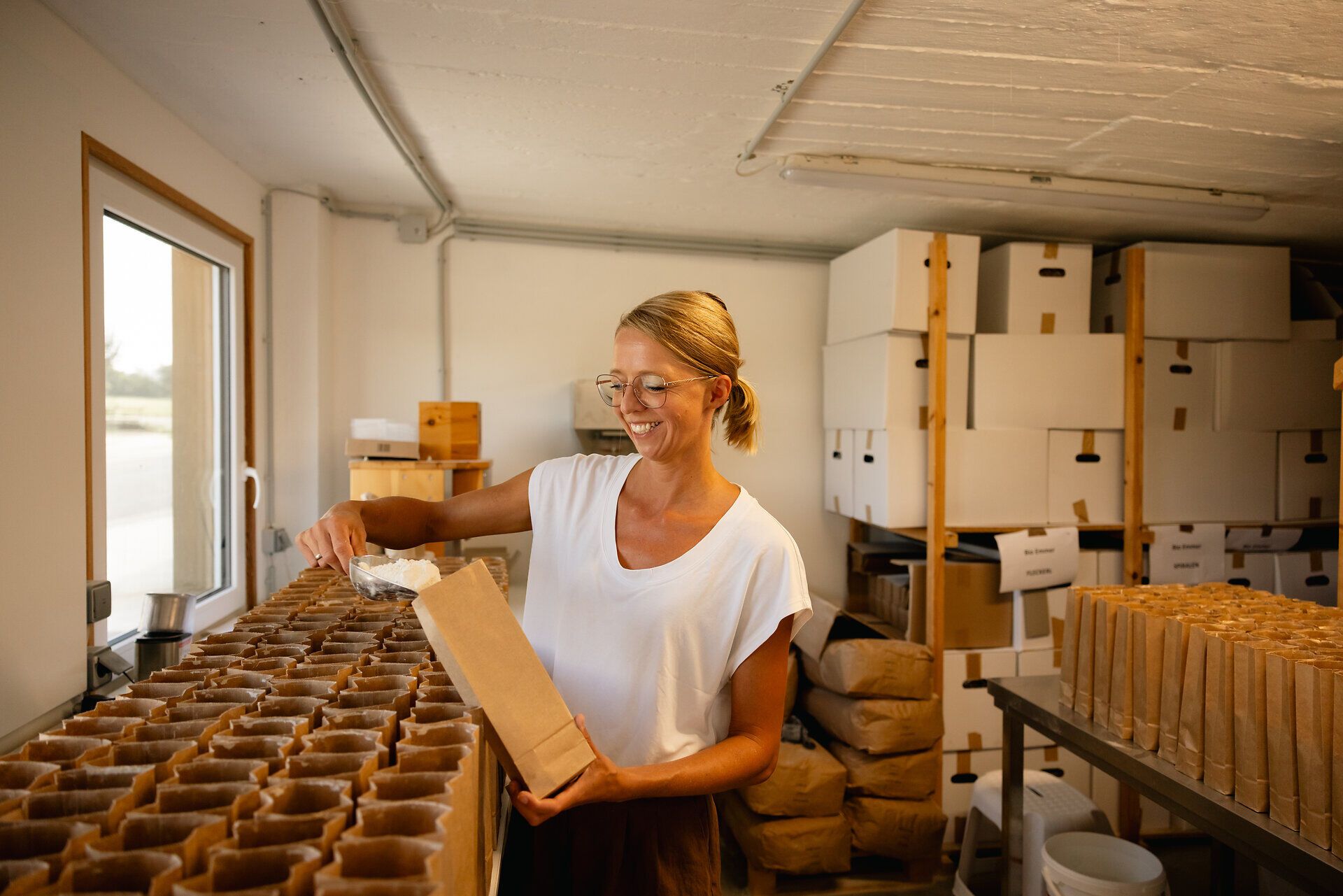 Frau füllt ein Produkt in Papiersäckchen ab.