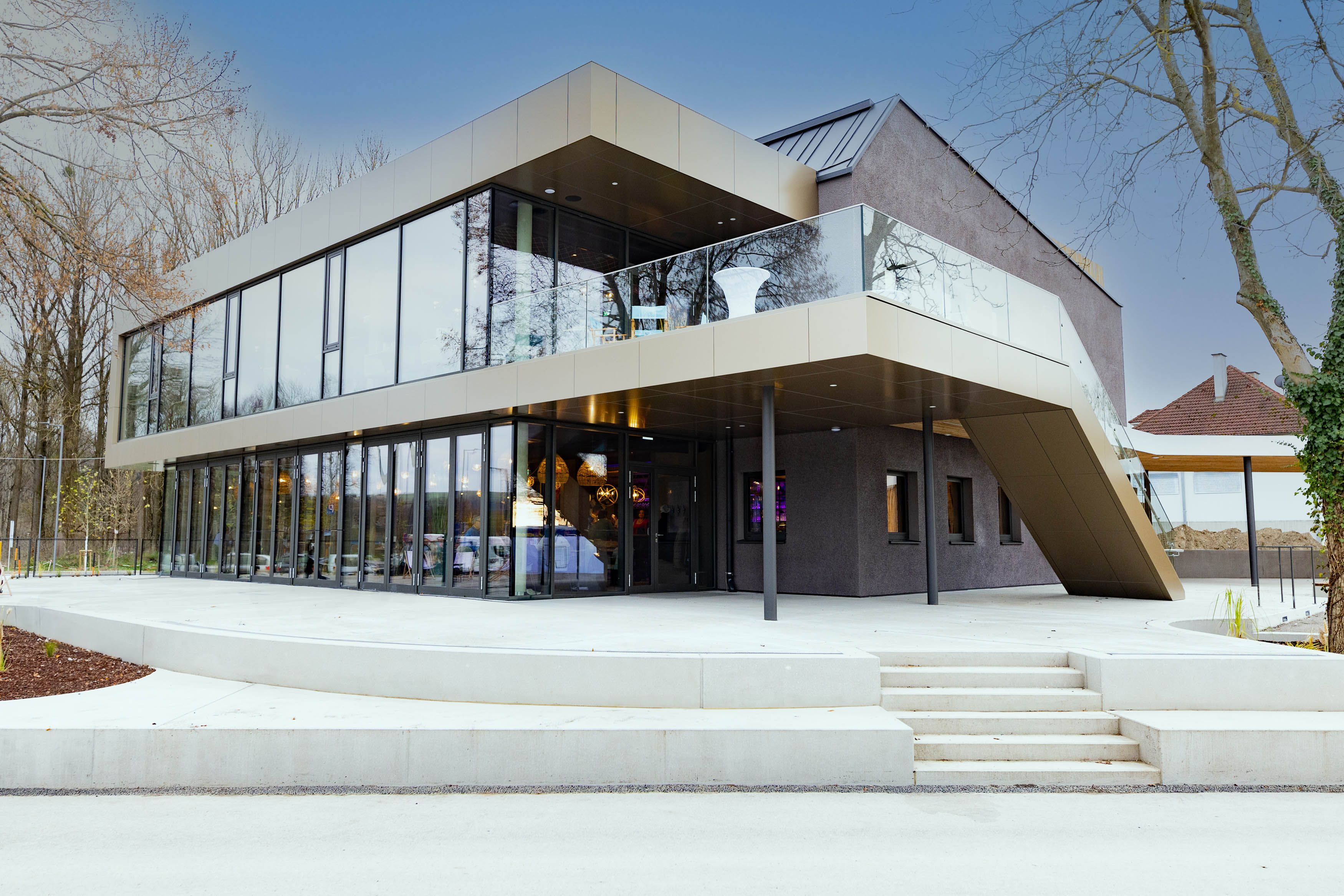 Moderne Gebäudeaußenansicht mit Glasfassade und Treppe.