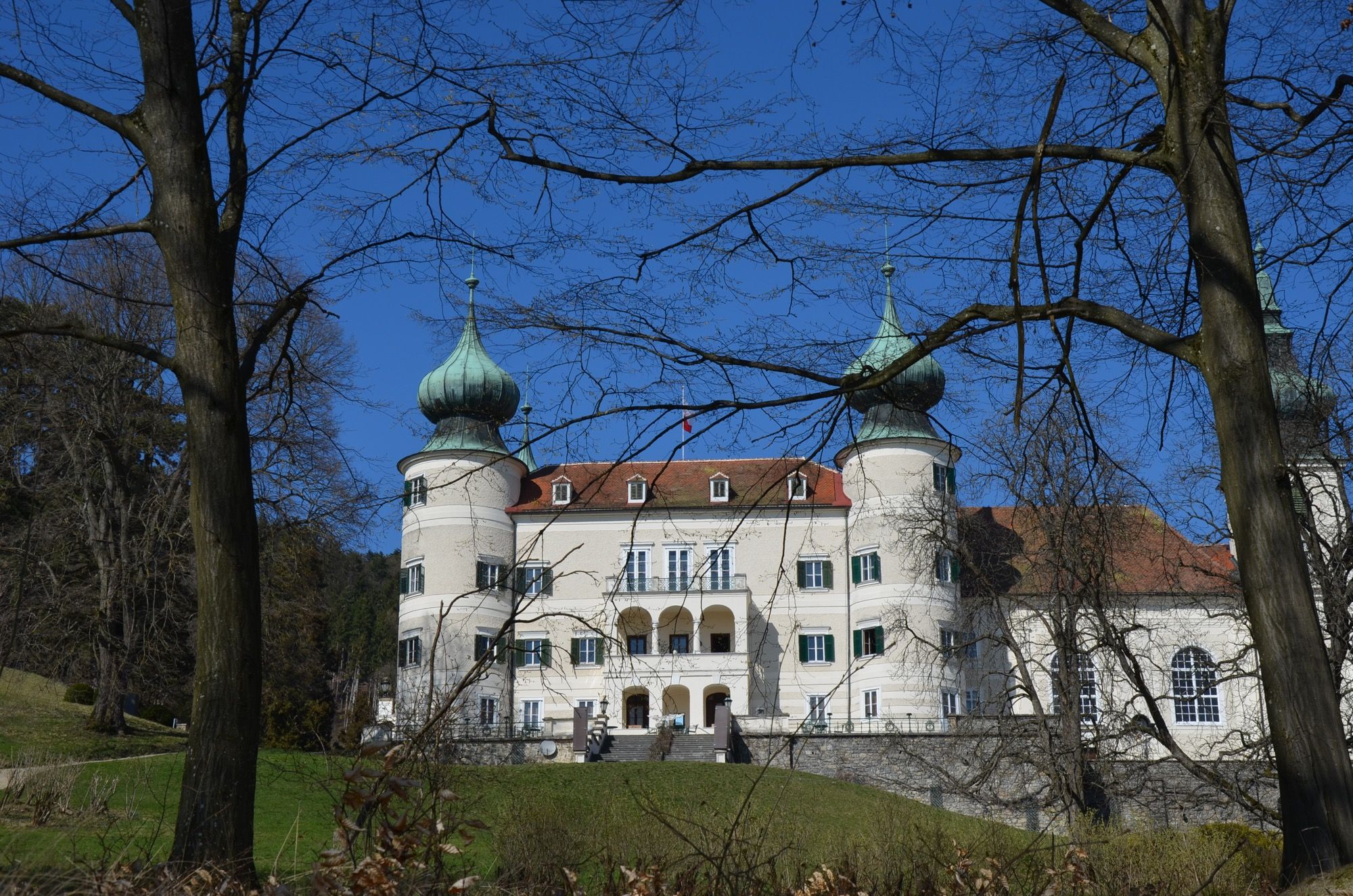 Schloss Artstetten mit zwei markanten Türmen und blauer Himmel im Hintergrund.