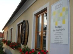 Außenansicht eines Weinguts mit Blumen und Schild.