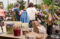 Leute sitzen im Innenhof, im Vordergrund Essen in kleinen Gläsern