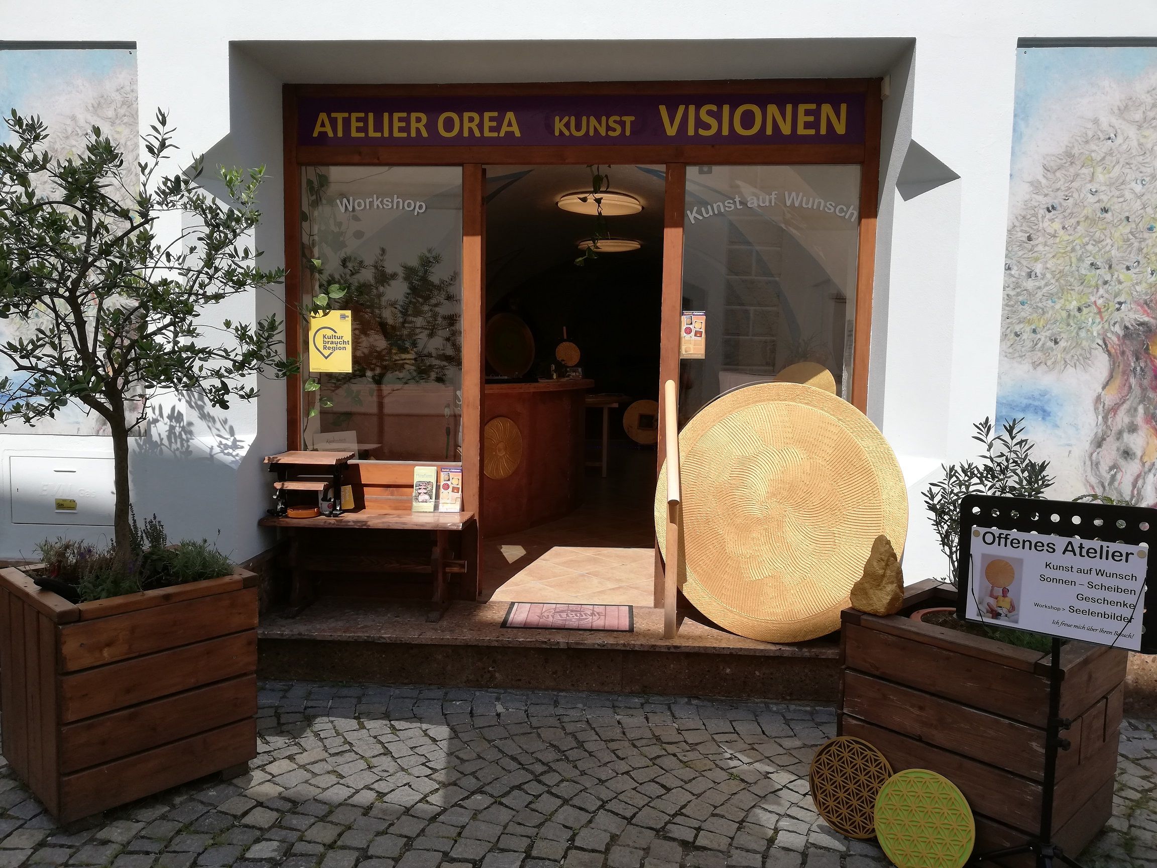 Eingang des Ateliers Orea mit Kunstwerken und Pflanzen.