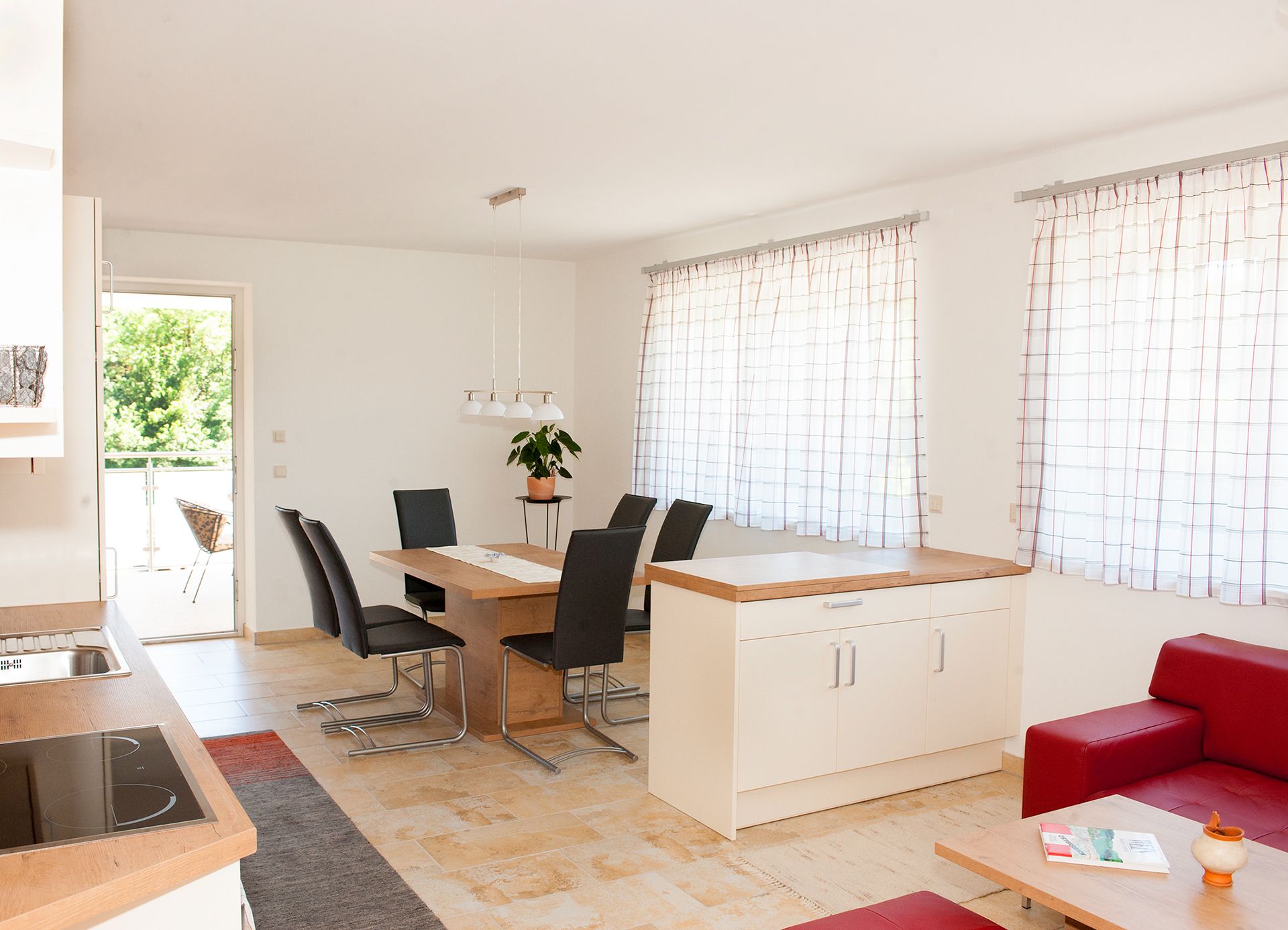 Moderner Essbereich mit Holztisch, schwarzen Stühlen und großen Fenstern mit Vorhängen.