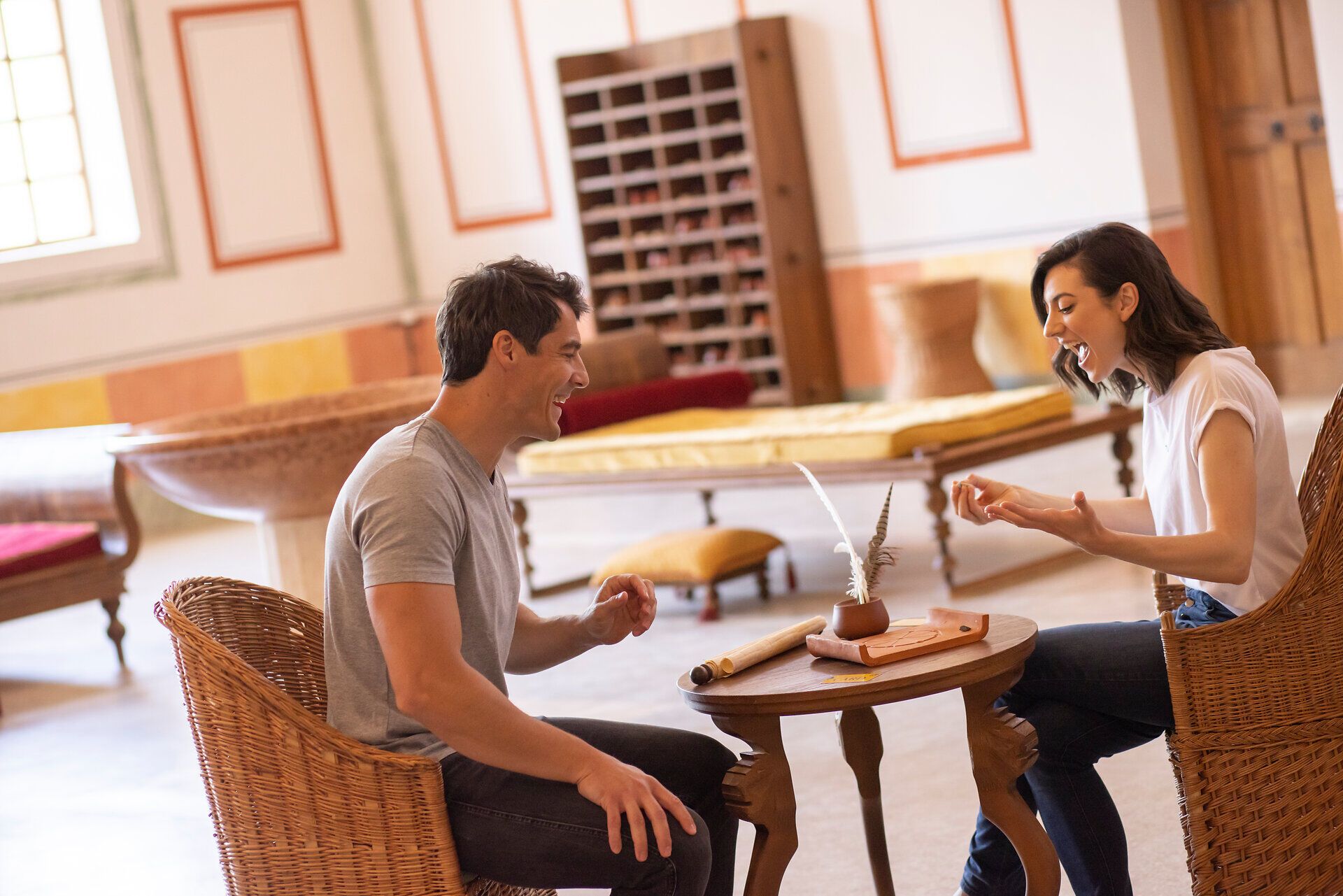In einem einladenden Raum voller natürlicher Materialien und warmen Farben lachen zwei Menschen fröhlich miteinander. Die entspannte Atmosphäre lädt dazu ein, die Zeit zu genießen und unvergessliche Momente zu teilen.