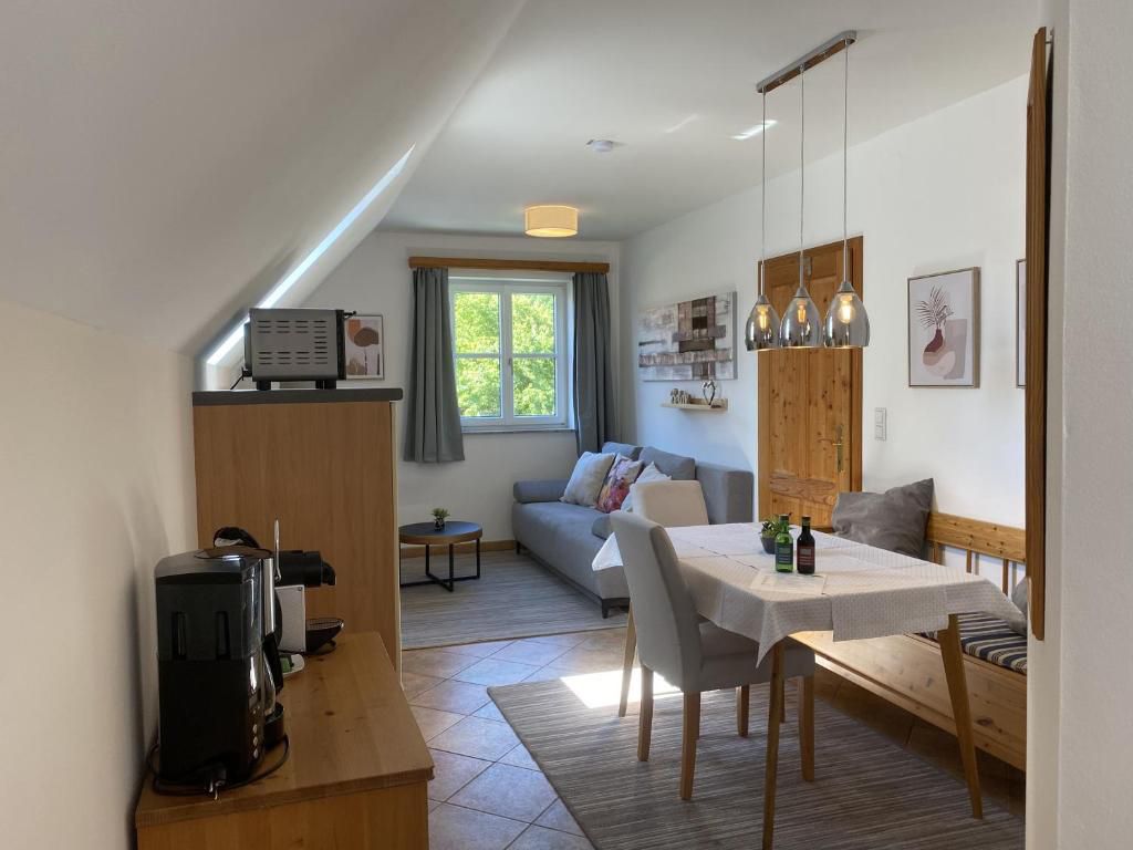 Gemütliches Wohnzimmer mit Esstisch, Sofa und Küchenzeile in einem Landhausstil.