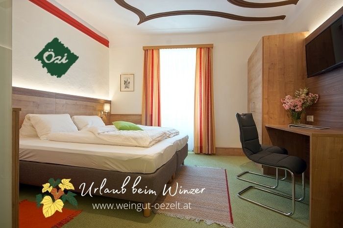 Gemütliches Gästezimmer mit Doppelbett, Schreibtisch und Stuhl, dekoriert mit Blumen. Helle Vorhänge und Teppichboden.