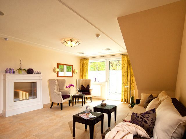 Ein gemütlicher Wellness-Ruhebereich mit Kamin, Sesseln, Sofa und Tischchen, dekoriert mit Kerzen und Pflanzen.