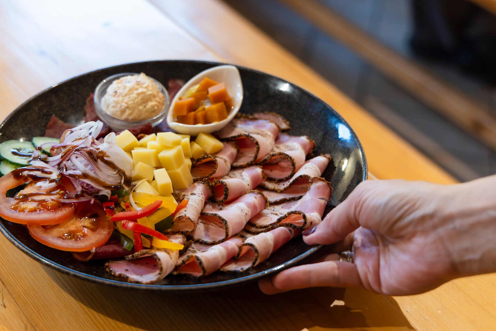 Heurigenplatte mit Fleisch wird an den Heurigentisch serviert. 