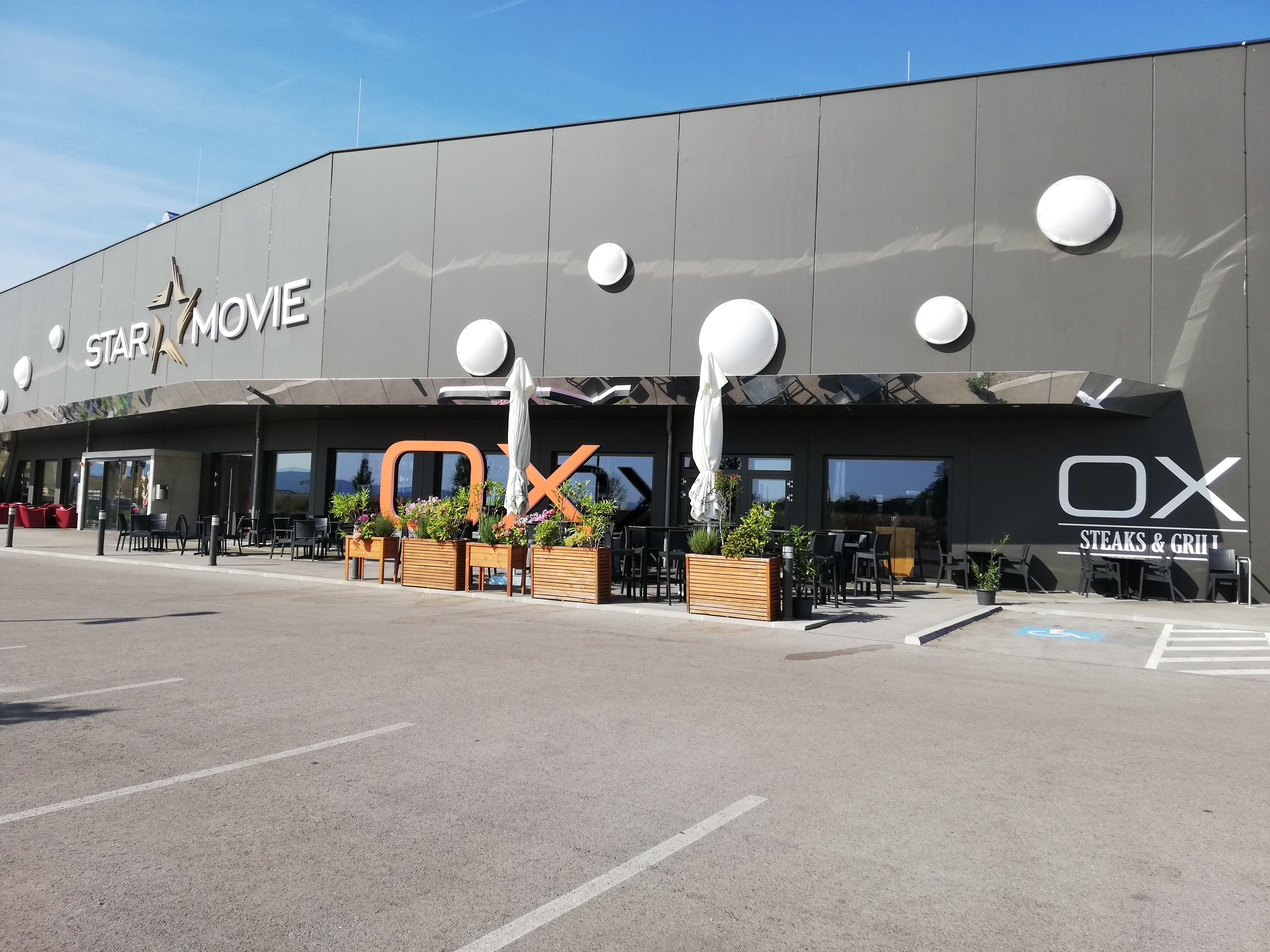 Außenansicht von Star Movie Kino und OX Steaks & Grill mit Terrasse.