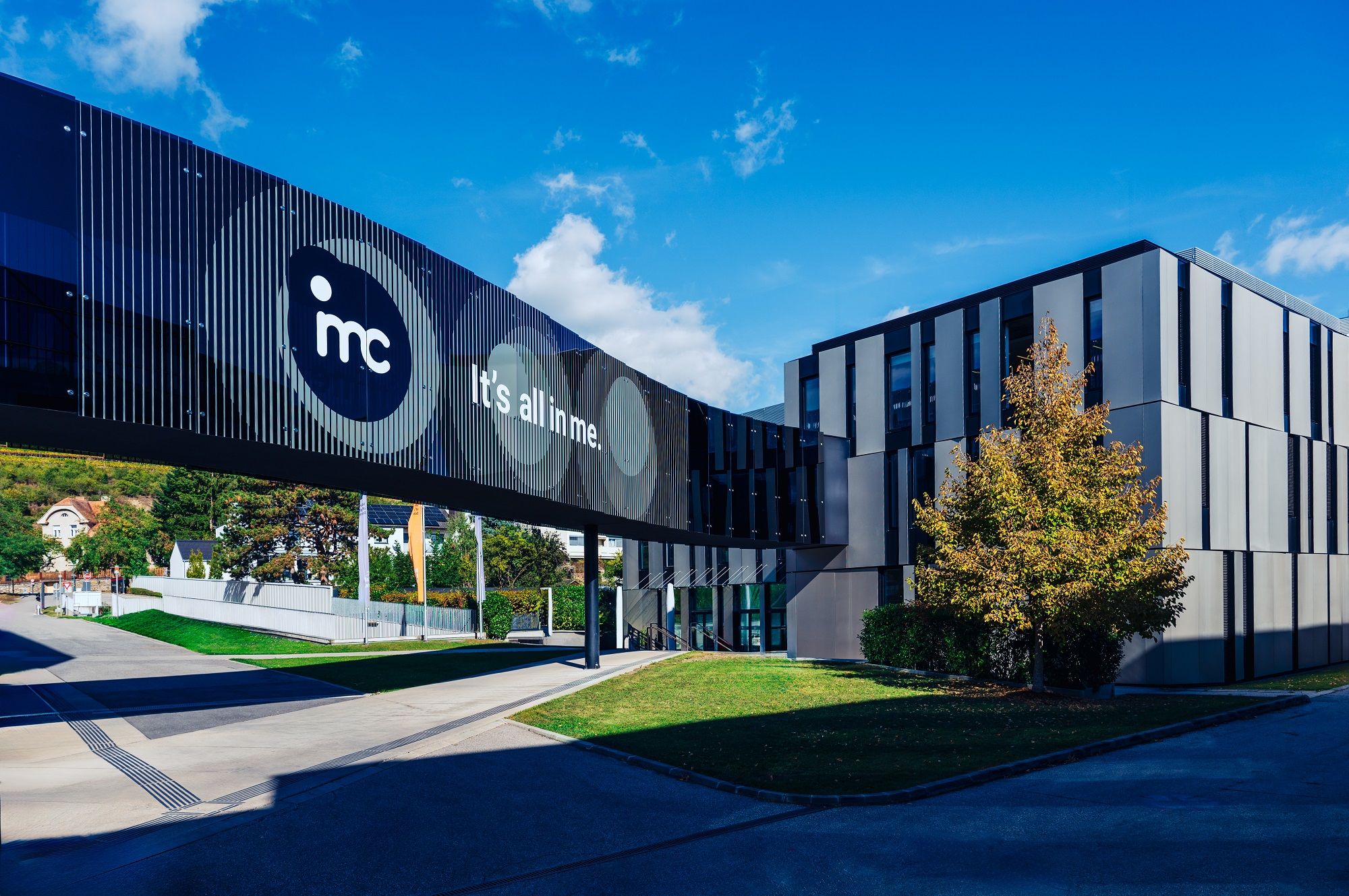 Modernes Gebäude der IMC Krems mit Glasbrücke und Schriftzug 'It's all in me'.