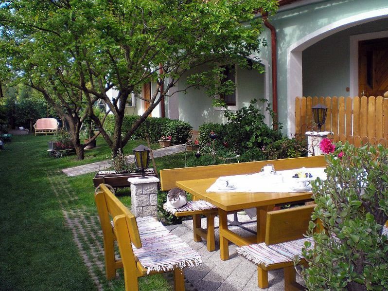 Ein gepflegter Garten mit Holzmöbeln, einer Katze auf der Bank und einem gedeckten Tisch.