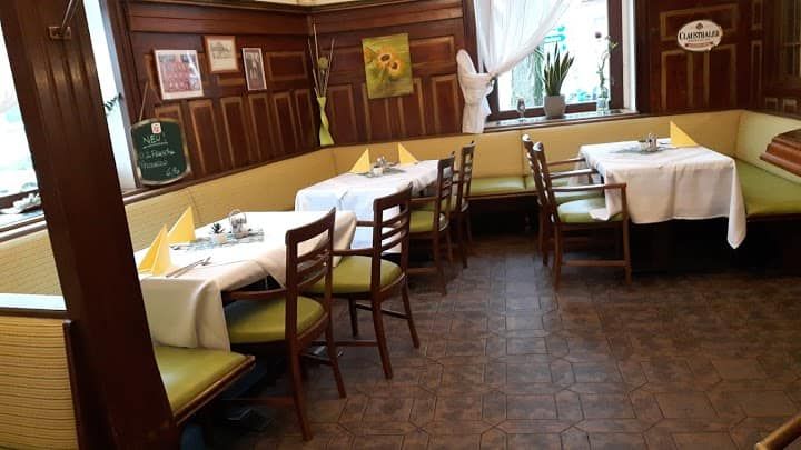 Gemütliches Restaurant mit Holzwänden, gedeckten Tischen und grünen Stühlen.