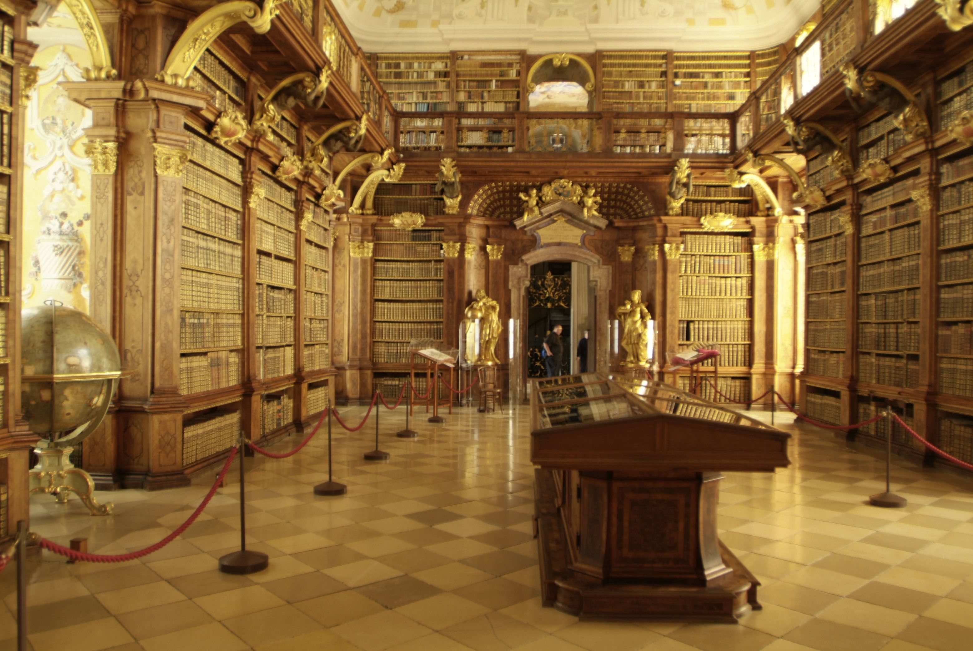 Innenansicht der Bibliothek im Stift Melk mit hohen Bücherregalen und goldenen Verzierungen.