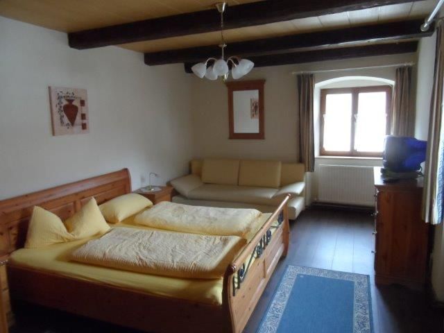 Gemütliches Doppelzimmer mit Holzbett, Sofa und Fenster.