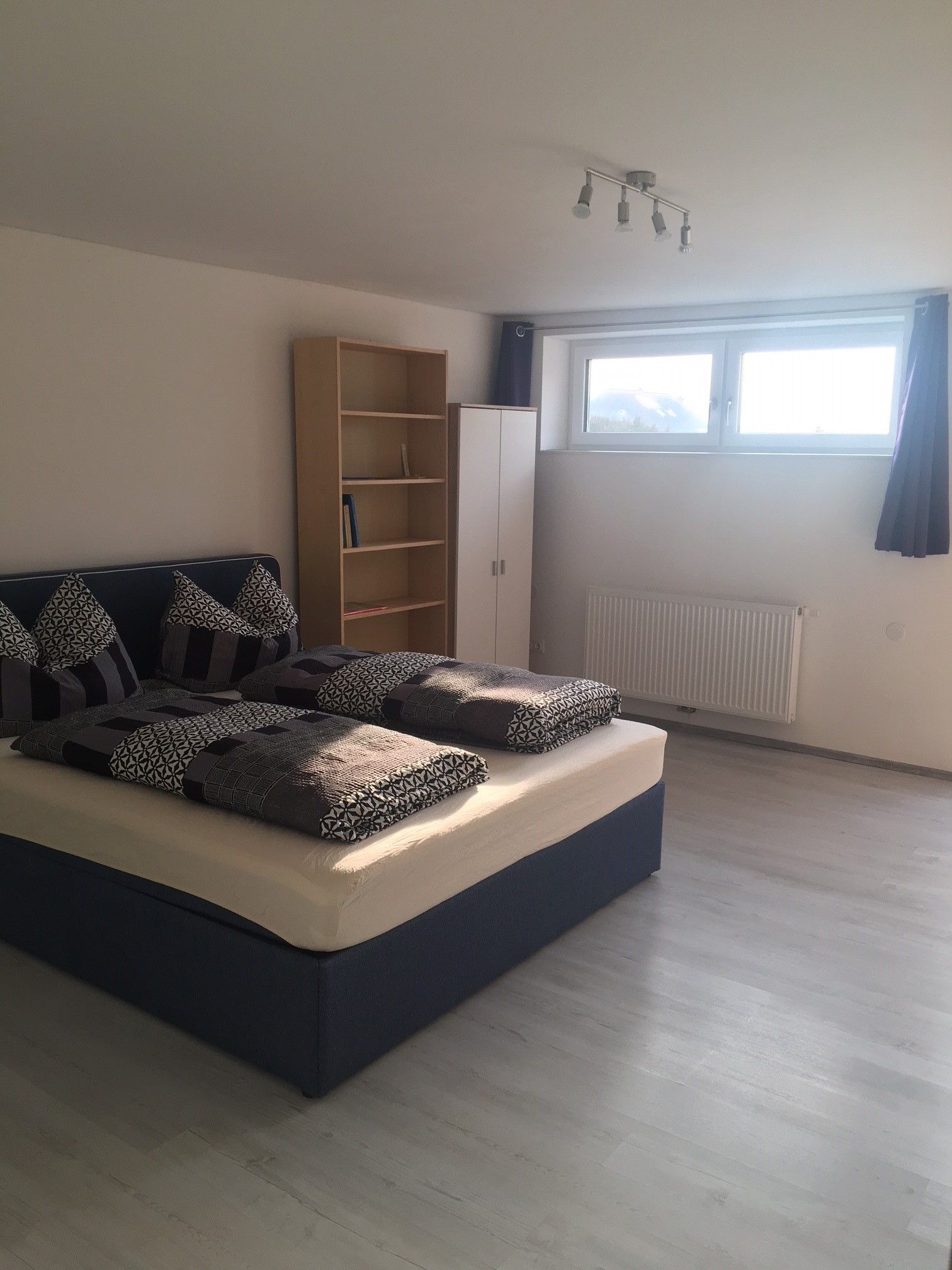 Schlafzimmer mit Doppelbett, Holzfußboden und Fenster 