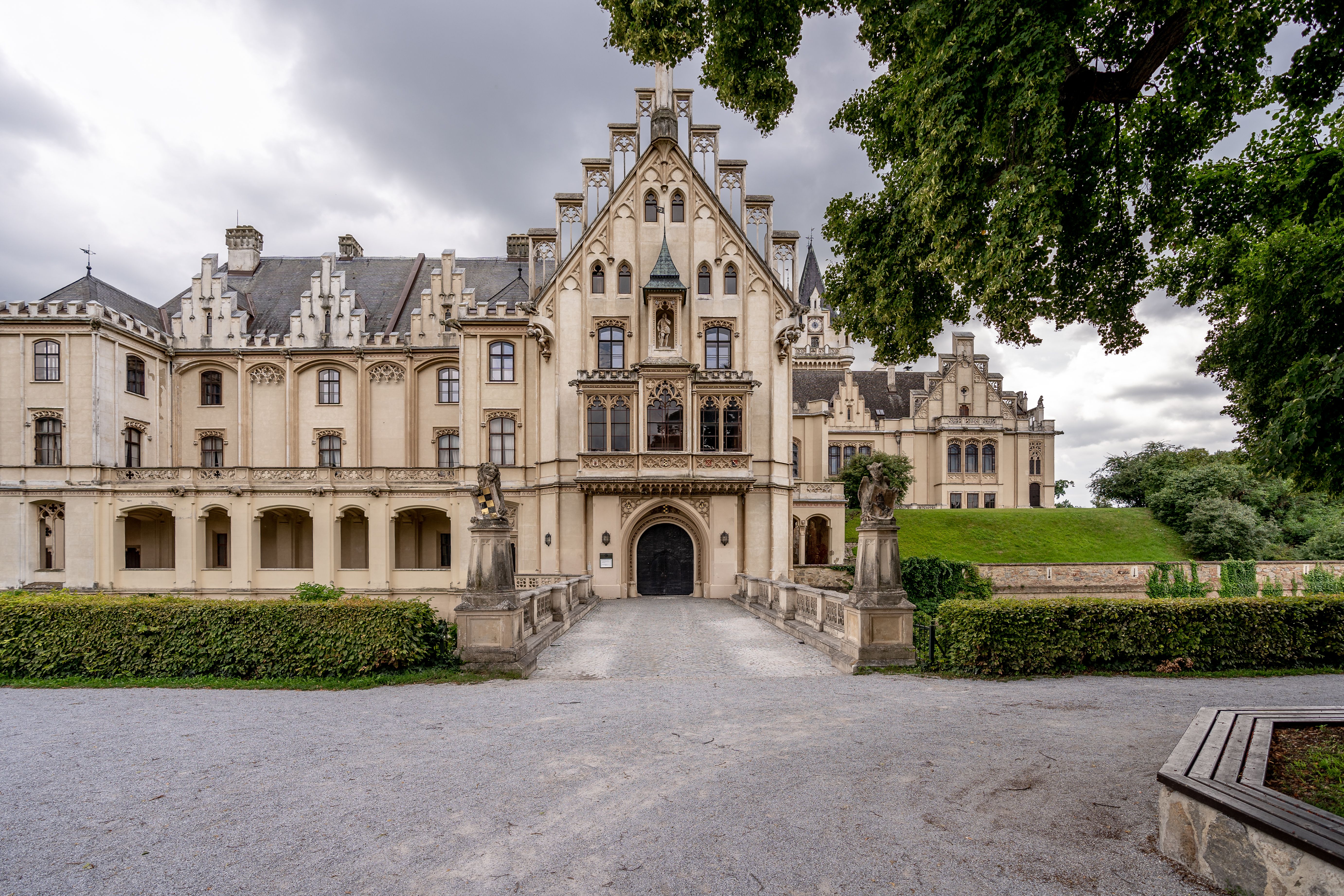 Schloss Grafenegg mit weitläufigem Rasen und Bäumen im Vordergrund.