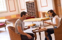 In einem einladenden Raum voller natürlicher Materialien und warmen Farben lachen zwei Menschen fröhlich miteinander. Die entspannte Atmosphäre lädt dazu ein, die Zeit zu genießen und unvergessliche Momente zu teilen.