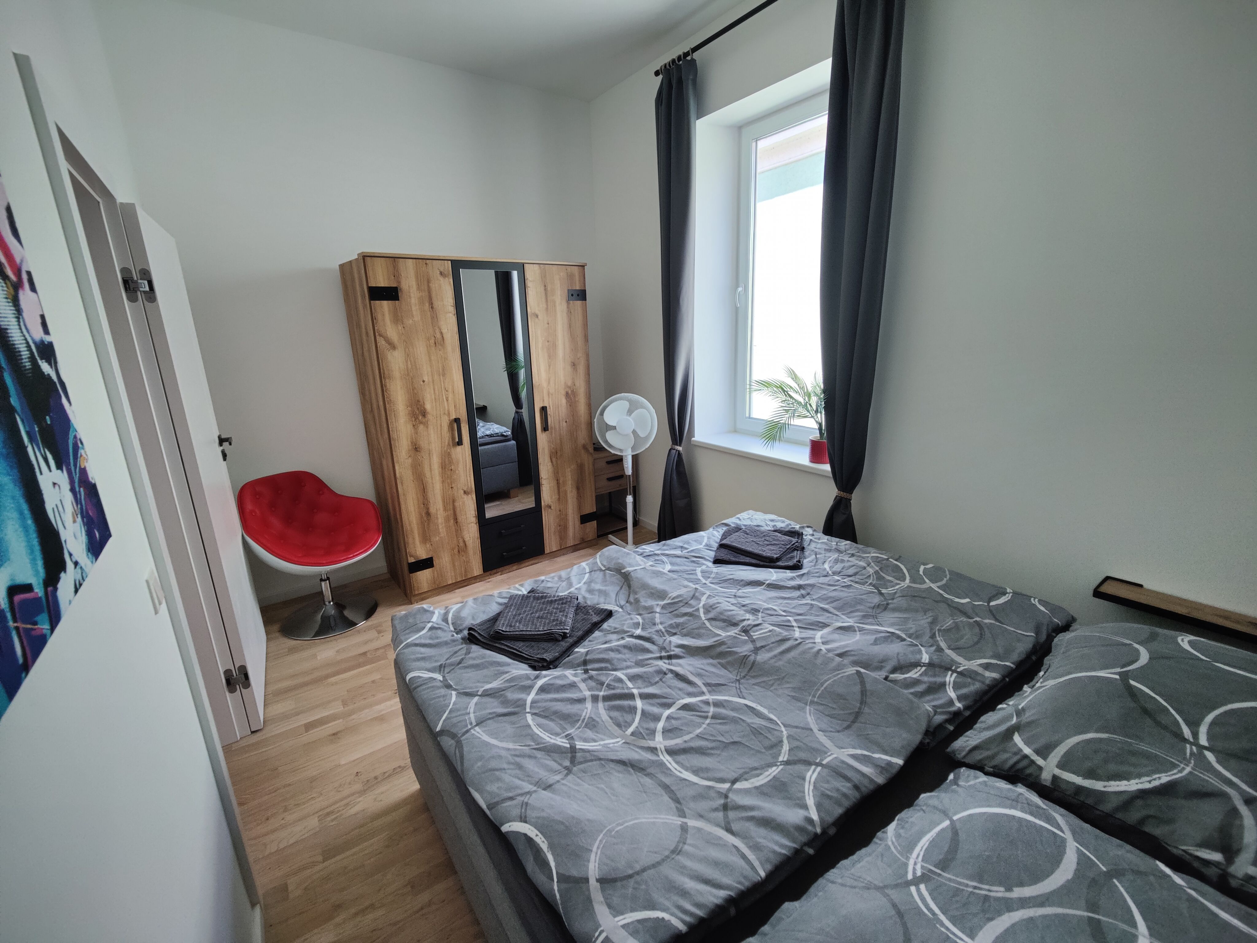 Schlafzimmer mit Holzboden und Fenster sowie Doppelbett und Kleiderschrank