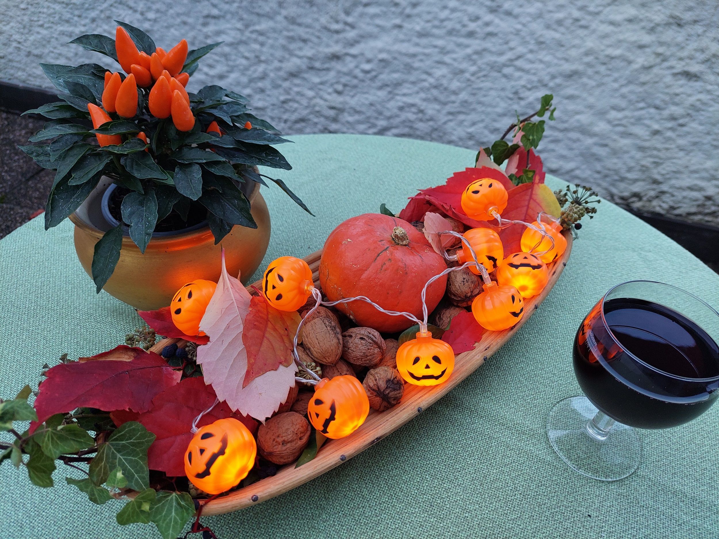 Herbstliche Tischdekoration mit Kürbis, Lichterkette und Getränk.